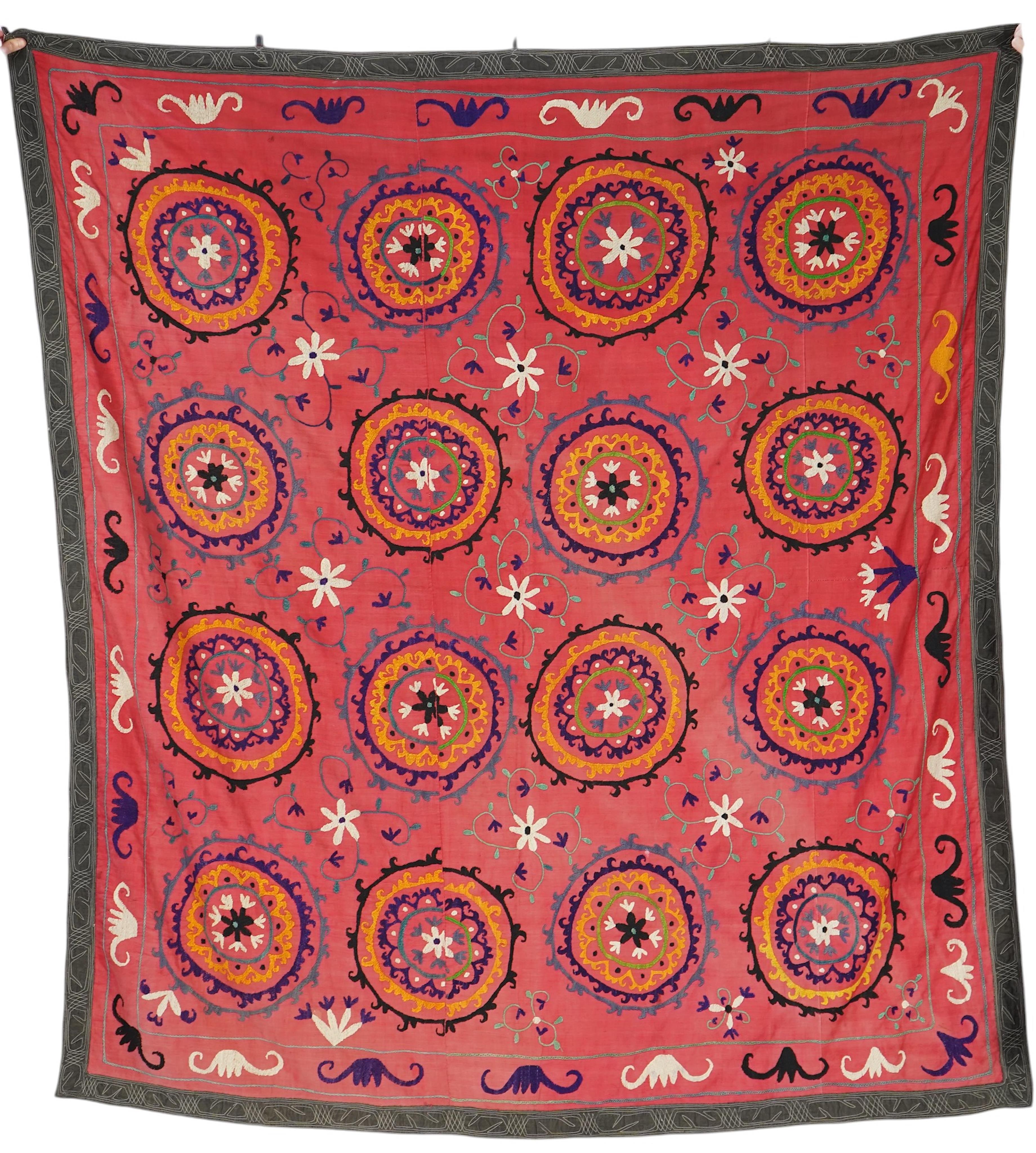 A large 20th century Uzbek multi coloured and embroidered Suzani wall hanging. The word Suzani meaning needlepoint in Farsi. Made in three panels embroidered on a rich dark red background, using large stylised multi colo